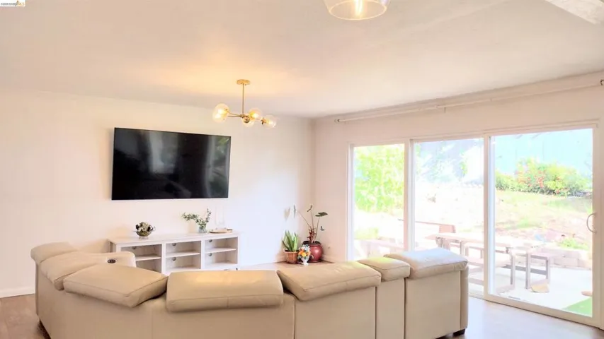 Living room featuring wood finished floors, a chandelier, and crown molding