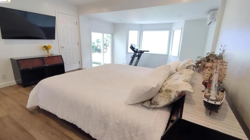 Bedroom with a mini split for heating / cooling and light wood-type flooring