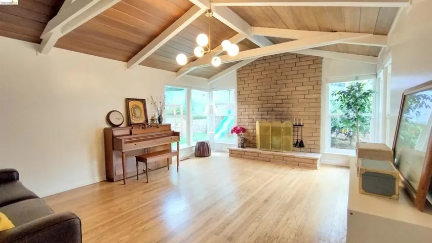 Living area featuring a wood ceiling with exposed beams, light wood-style flooring, a fireplace, and hanging lights