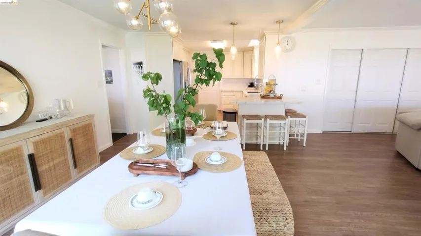 Dining space with hanging lights, dark wood-style floors, and crown molding