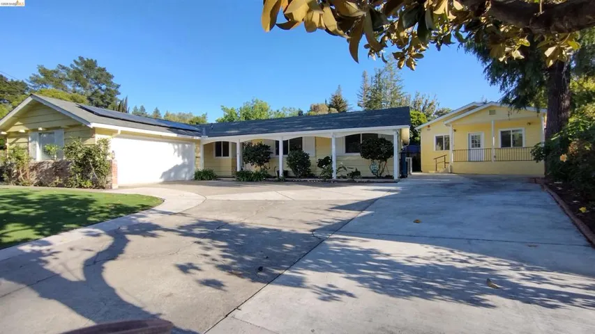 View of front of house featuring driveway, a garage, solar panels, and a front yard