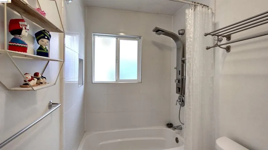 Full bathroom featuring shower / bathtub combination with curtain and toilet