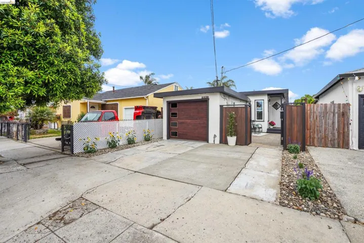 View of front facade featuring a fenced front yard, stucco siding, driveway, and a garage