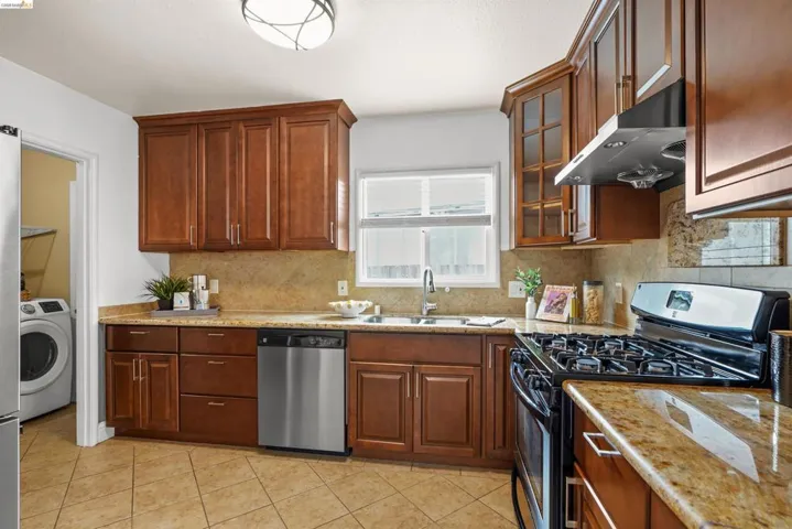Kitchen featuring range with gas stovetop, dishwasher, light stone counters, and light tile patterned flooring