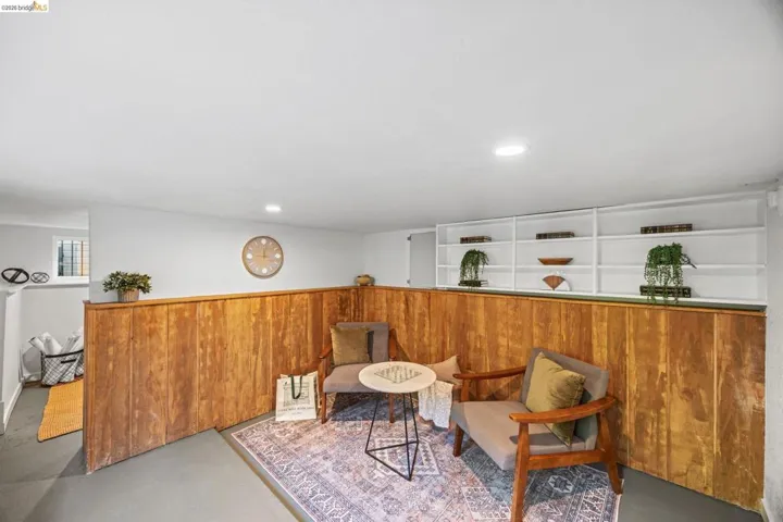 Sitting room with finished concrete floors, wood walls, wainscoting, and recessed lighting