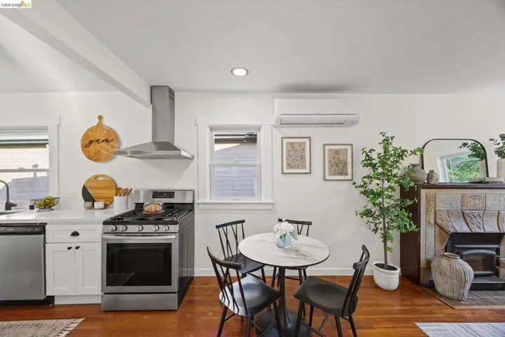 Kitchen with stainless steel appliances, white cabinetry, a fireplace, recessed lighting, and dark wood-style floors