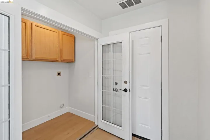 Laundry room with light wood-style flooring, cabinet space, and hookup for an electric dryer