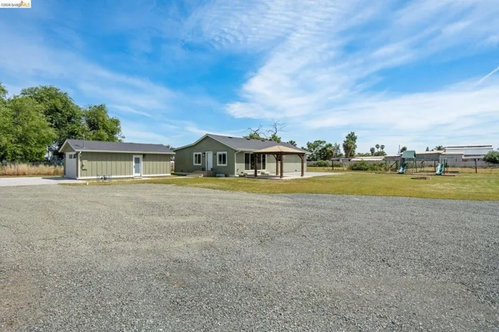 View of front of property with a gazebo, driveway, an outbuilding, a patio area, and a front lawn