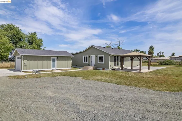 Ranch-style home featuring a patio area, a gazebo, a front yard, an outbuilding, and board and batten siding