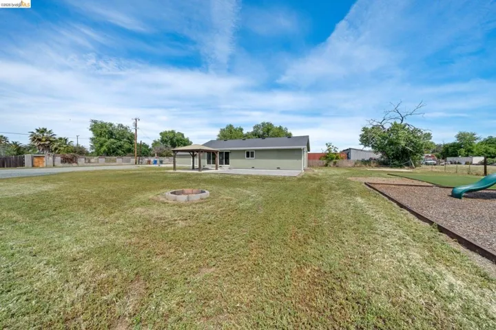 Back of house featuring a patio, an outdoor fire pit, a gazebo, and a playground