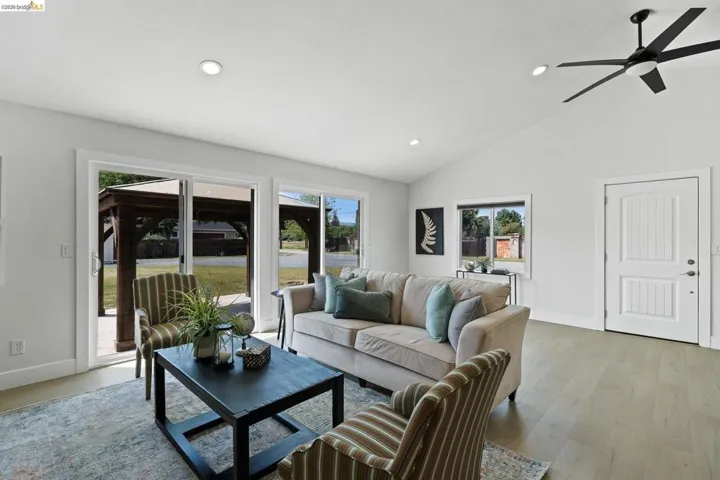 Living room featuring light wood finished floors, ceiling fan, lofted ceiling, and recessed lighting