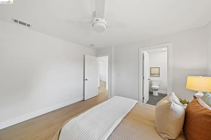 Bedroom with wood finished floors, a ceiling fan, and connected bathroom