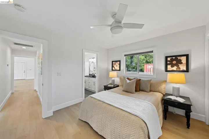 Bedroom featuring light wood-style flooring, connected bathroom, and a ceiling fan