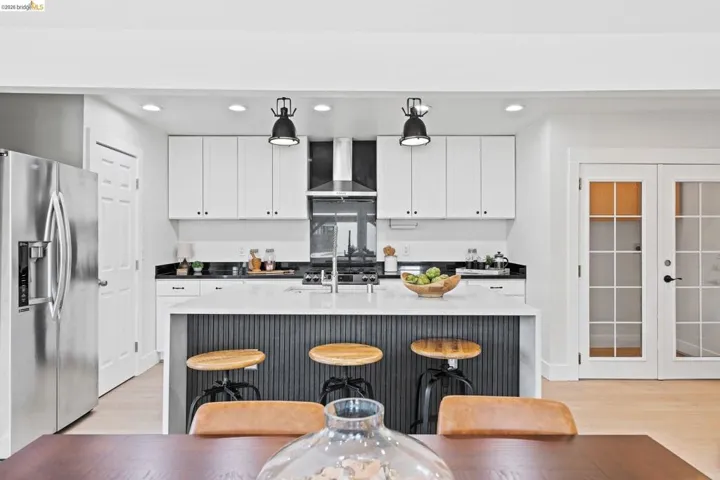 Kitchen featuring stainless steel refrigerator with ice dispenser, french doors, dark stone countertops, white cabinetry, and recessed lighting