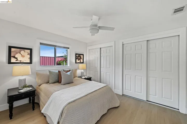 Bedroom with multiple closets, light wood-style flooring, and a ceiling fan