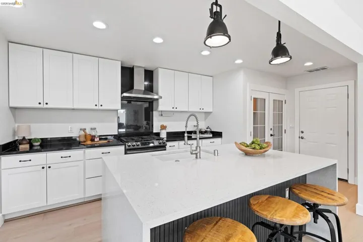 Kitchen with dark stone counters, white cabinets, and light wood-type flooring