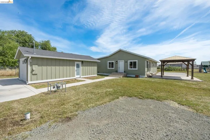 Rear view of house with board and batten siding, a gazebo, a yard, and roof with​​‌​​​​‌​​‌‌​​‌​​​‌‌​​​‌​​‌‌​​‌‌​​‌‌​​​​ shingles