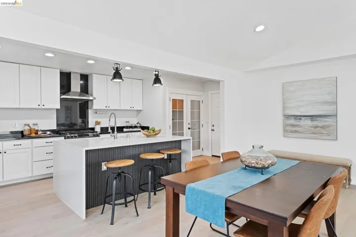 Kitchen featuring white cabinetry, light wood-style floors, a kitchen breakfast bar, dark stone countertops, and recessed lighting
