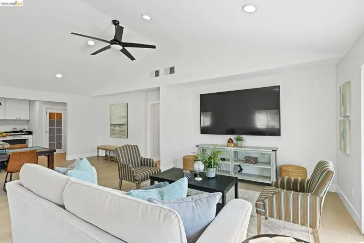 Living room with light wood-type flooring, a ceiling fan, recessed lighting, and vaulted ceiling