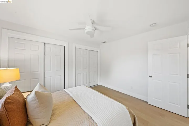 Bedroom featuring two closets, light wood-style floors, and ceiling fan