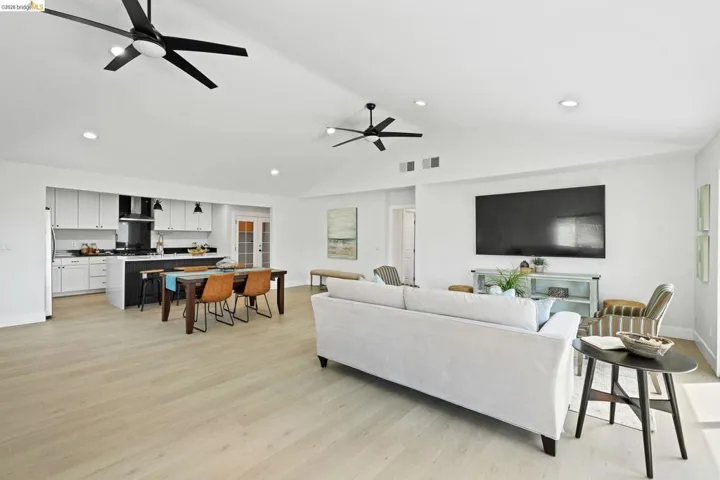 Living area with light wood-type flooring, a ceiling fan, recessed lighting, and lofted ceiling