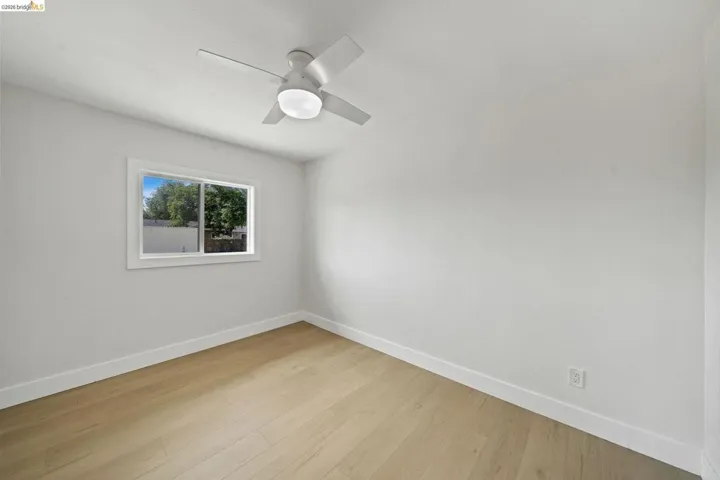Empty room with light wood-style floors and a ceiling fan