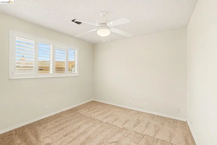 Upstairs bedroom 2 with new carpet, ceiling fan, shutters, dual pane windows