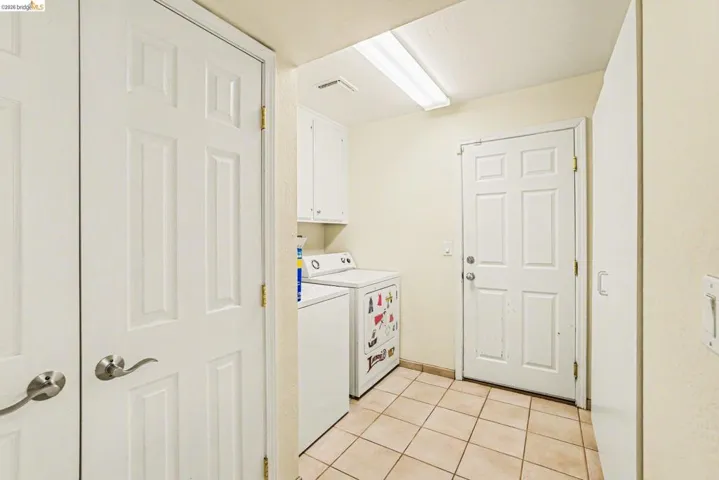 Laundry room with tile floors, separate washer and dryer, cabinet space and free-standing cabinet