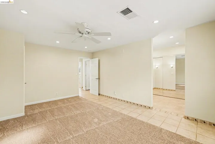 Master bedroom/dressing area with ceiling fan, new carpet, recessed lighting, tile floors and mirrored closet doors.