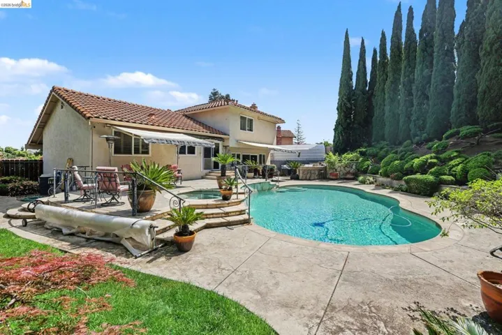 View of swimming pool with an in-ground hot tub, patio surround, and a fenced backyard