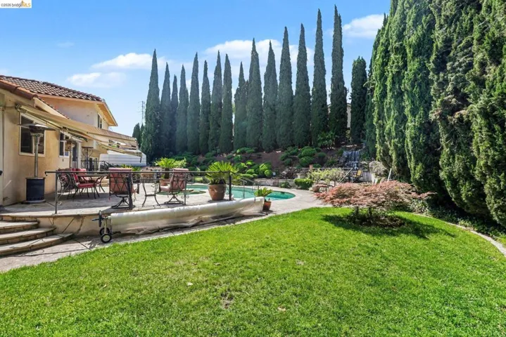View of grassy yard featuring an outdoor pool, outdoor dining space, and a patio