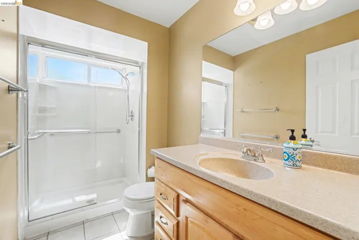 Bathroom featuring vanity, a shower stall, and tile flooring