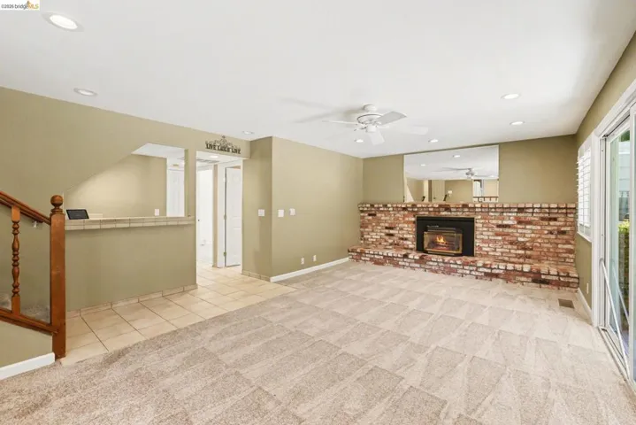 Family room with new carpet, recessed lighting, ceiling fan, brick fireplace with gas insert, tile flooring