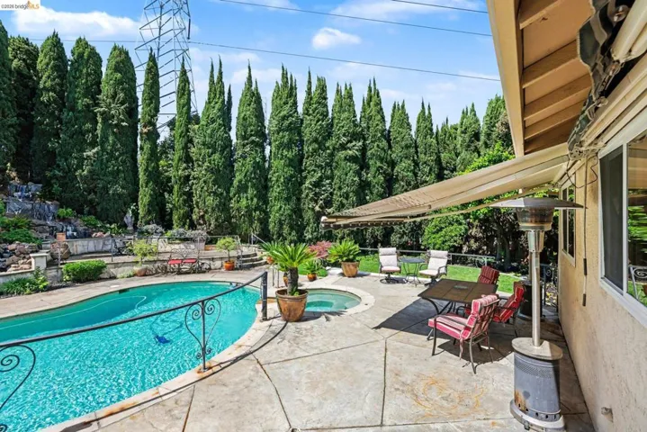 View of pool featuring patio surround and view of scattered trees