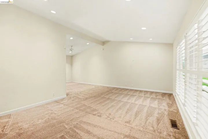 Living Room featuring vaulted ceiling, new carpet, recessed lighting, Shutters and dual pane windows.