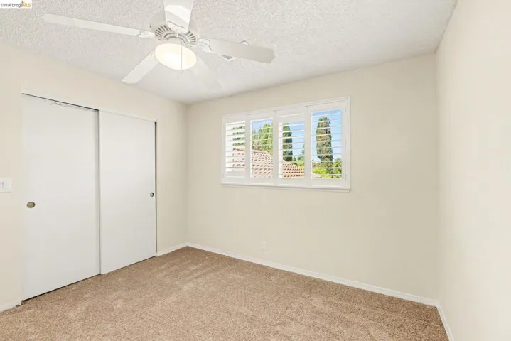 Upstairs Bedroom 2 with new carpet, a closet with light, ceiling fan, shutters and dual pane window