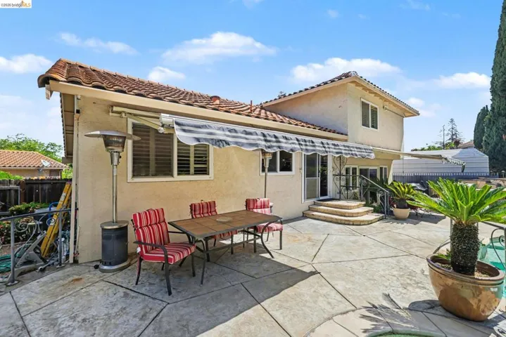 Rear view of house featuring stucco siding, a patio area, outdoor dining area, and a tiled roof