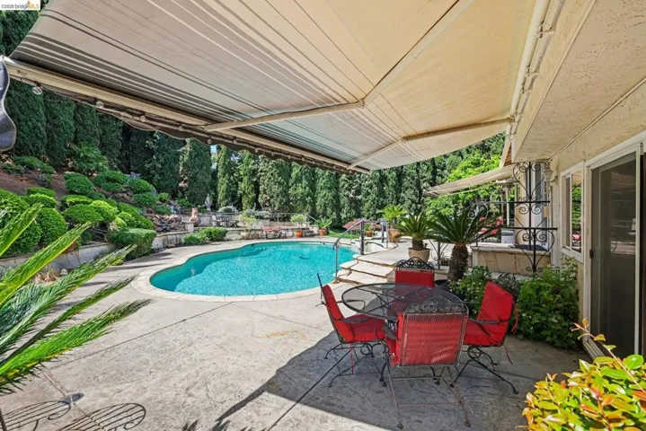 Swimming pool with a patio, view of scattered trees, and outdoor dining area