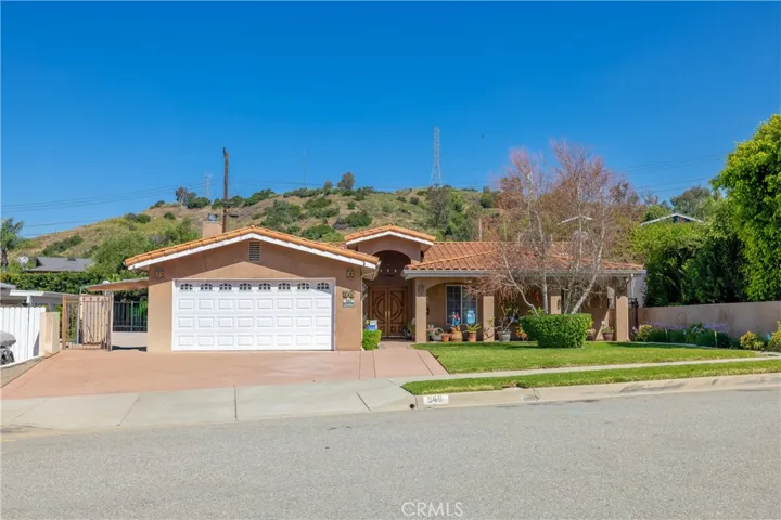 Well-maintained front exterior with wide driveway, 2-car garage, and hillside backdrop.