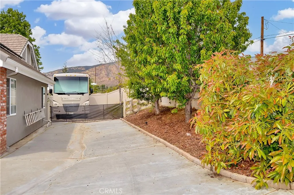 RV parking with hook-ups behind the retractable fencing with parking for more cars/toys on the side of the garage. Yes, those are fruit trees on the right - including delicious avocados.