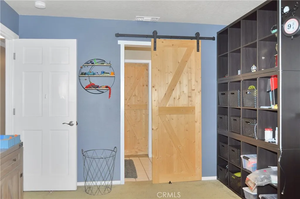 The 2nd bedroom is across the hall from the main suite and offers barn door access to the "Jack and Jill" bath, louvered shutters, a ceiling fan, and a deep closet