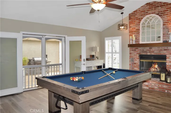 The family room/game room features a cozy brick fireplace with raised hearth (fire added virtually), cathedral ceilings, custom lighting, French doors to the backyard patio, more fabulous flooring, and handy storage cabinets. Yes, the pool table is included and it has a ping pong table top, too, for added fun!