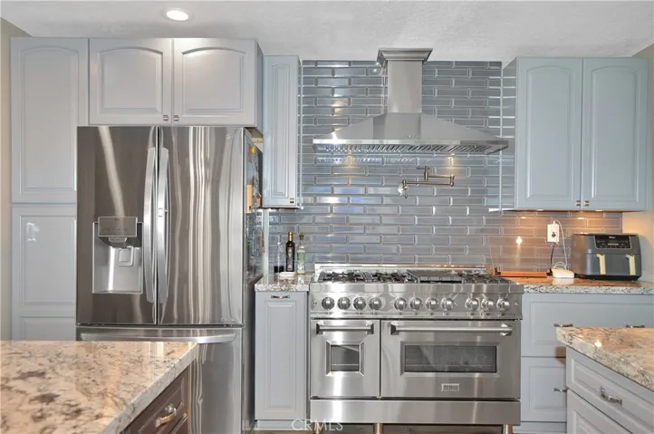 Gorgeous, professional-grade range with pot filler and stylish hood above and full tile backsplash behind. Yes, the refrigerator is also included.