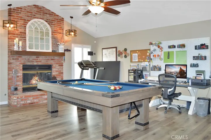 The family room/game room features a cozy brick fireplace with raised hearth (fire added virtually), cathedral ceilings, custom lighting, French doors to the backyard patio, more fabulous flooring, and handy storage cabinets. Yes, the pool table is included and it has a ping pong table top, too, for added fun! (Screen image added virtually)