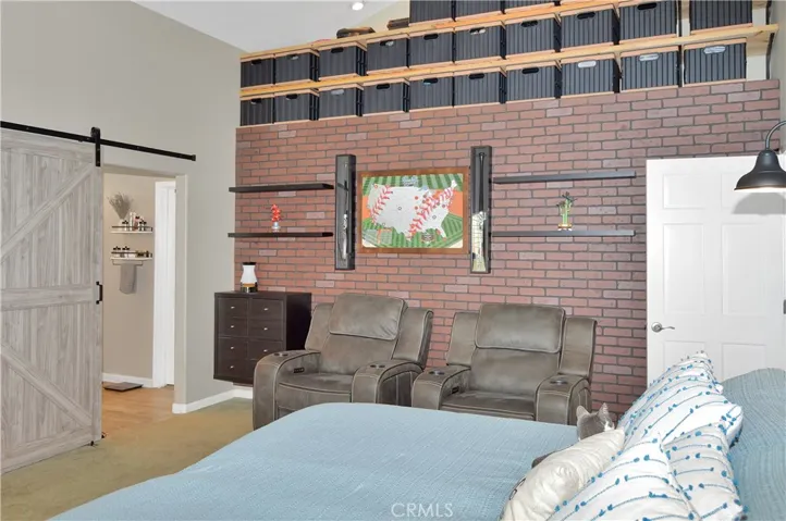The spacious main bedroom suite boasts more custom built-ins with another heated fireplace and display shelves surrounding the TV (included), a matching lighted headboard (included), brick accent wall with cabinet and shelving, dramatic cathedral ceilings, louvered shutters, a fantastic fan, and a barn door leading to the en suite bath.
