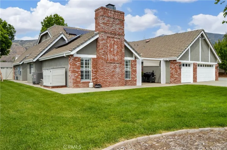 Now we can explore the backyard! Let's start with the inviting lawn with concrete pathways around the house and a patio tucked between the family room and the garage. This is one of the three storage sheds which are all included. Did you notice the near-new AC condenser (upgraded in 2024) and the money-saving solar panels?