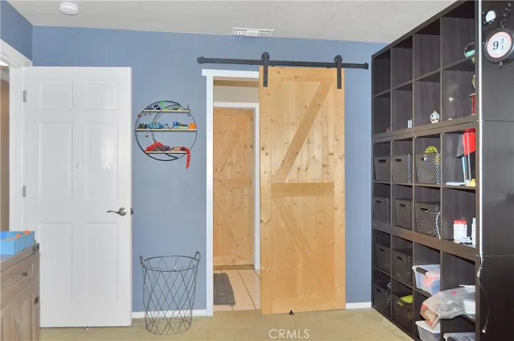 The 2nd bedroom is across the hall from the main suite and offers barn door access to the "Jack and Jill" bath, louvered shutters, a ceiling fan, and a deep closet