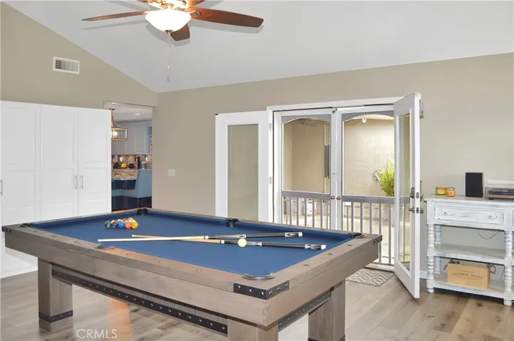 The family room/game room features a cozy brick fireplace with raised hearth, cathedral ceilings, custom lighting, French doors to the backyard patio, more fabulous flooring, and handy storage cabinets. Yes, the pool table is included and it has a ping pong table top, too, for added fun!