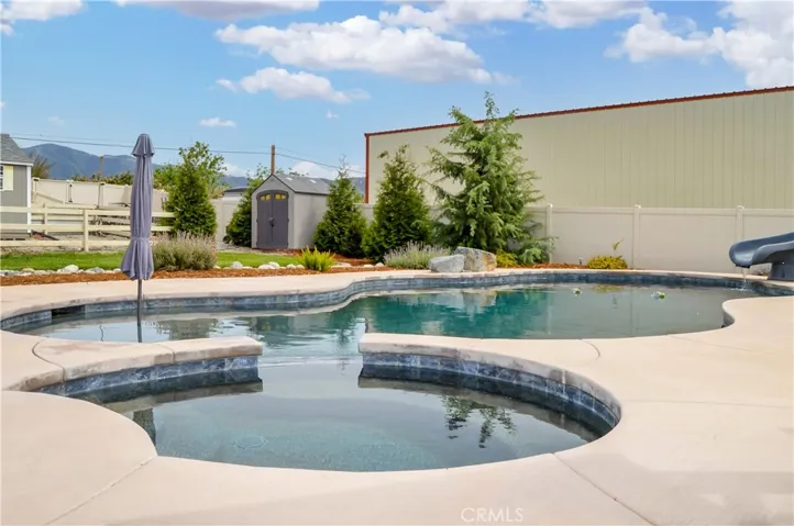 The sparkling pool and spa were built in 2021 and include a dark bottom PebbleTec surface for better heat retention (but they have heaters, too), a UV sterilization system, a water slide, a jumping rock, a Baja reef area with umbrella, a lighted gazebo with a fireplace included (fire added virtually), towel rack, concrete decking for sunbathing, lawn area for relaxing, and a handy storage shed. Pool party anyone?