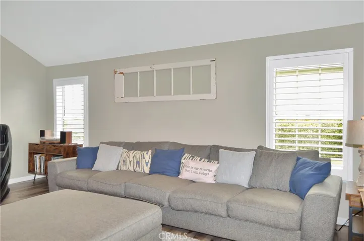 The living room is right next to the entry and features a stunning, custom built-in with heated fireplace, mantel, and display shelves, along with pet-friendly flooring, an impressive ceiling fan, and louvered shutters. The TV and extra-long couch are both negotiable.
